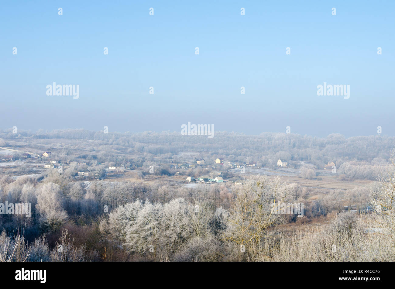 Nebbia di mattina e smerigliati erba e alberi fromtop della collina, sotto sono piccole capanne o case della contea. Foto Stock