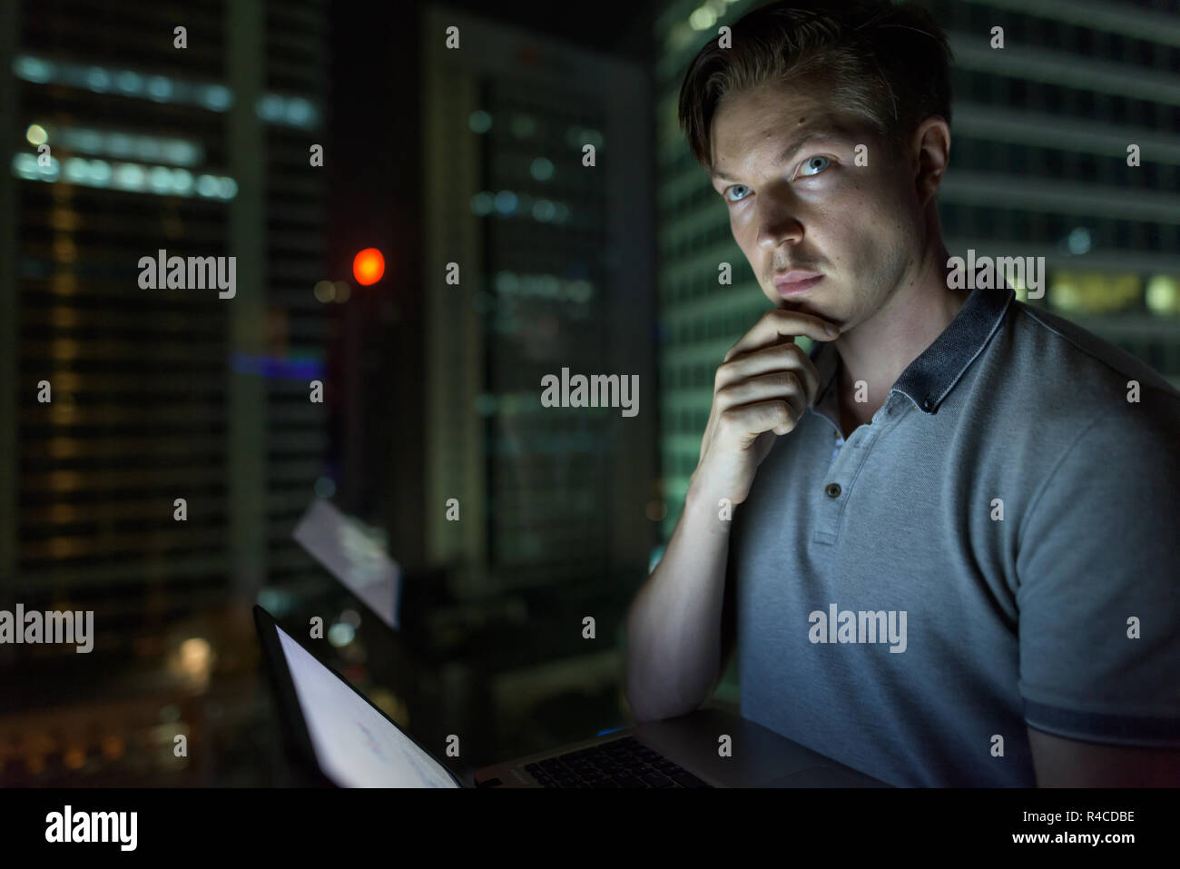 Giovane uomo bello utilizzando laptop contro il vetro della finestra con vista o Foto Stock