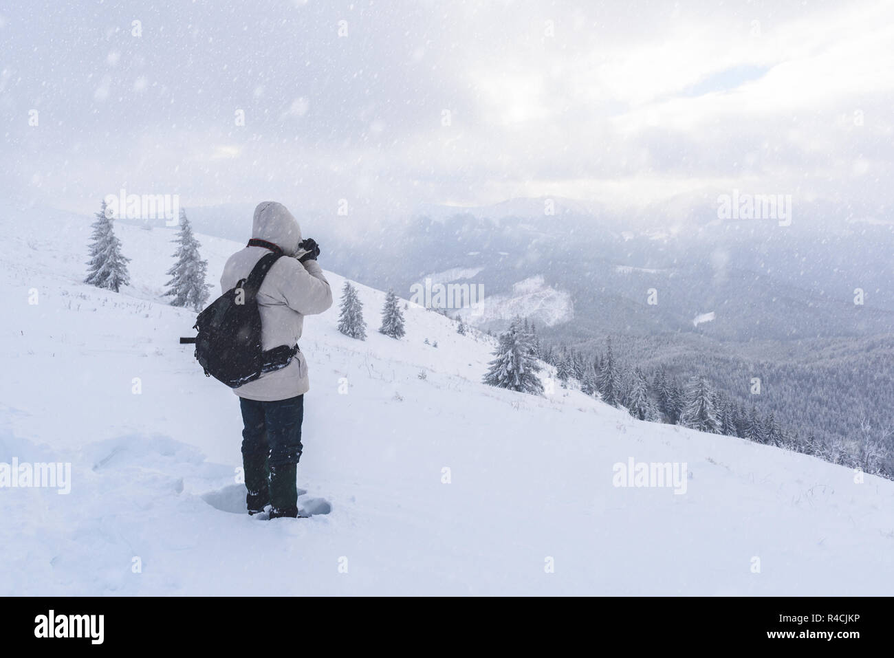 Fotografo da solo sulla cima della montagna nella tempesta di neve con uno zaino in inverno. Concetto di viaggio. Le montagne dei Carpazi. Fotografia di paesaggi Foto Stock