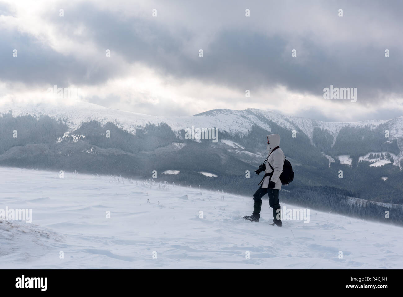 Fotografo da solo sulla cima della montagna nella tempesta di neve con uno zaino in inverno. Concetto di viaggio. Le montagne dei Carpazi. Fotografia di paesaggi Foto Stock