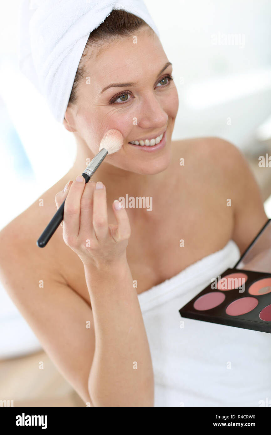 Donna sorridente nel bagno di applicare il trucco su Foto Stock