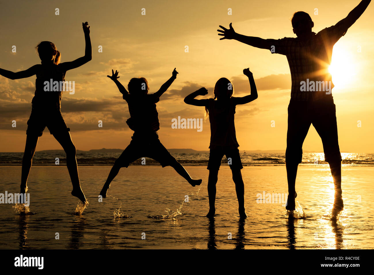 Padre e figli giocando sulla spiaggia al tramonto. Foto Stock