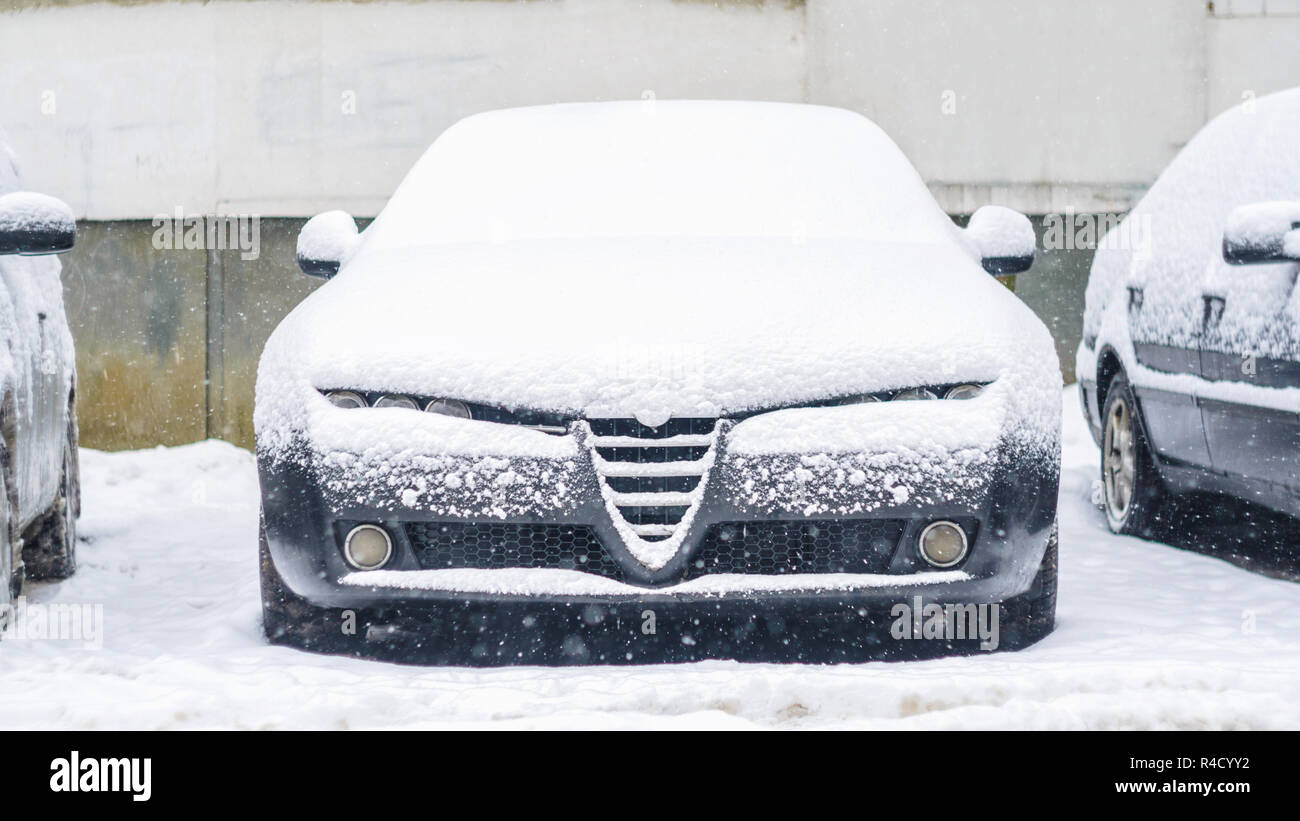 Vista frontale di una macchina in piedi nel parcheggio e coperto con uno strato di neve in inverno. Foto Stock