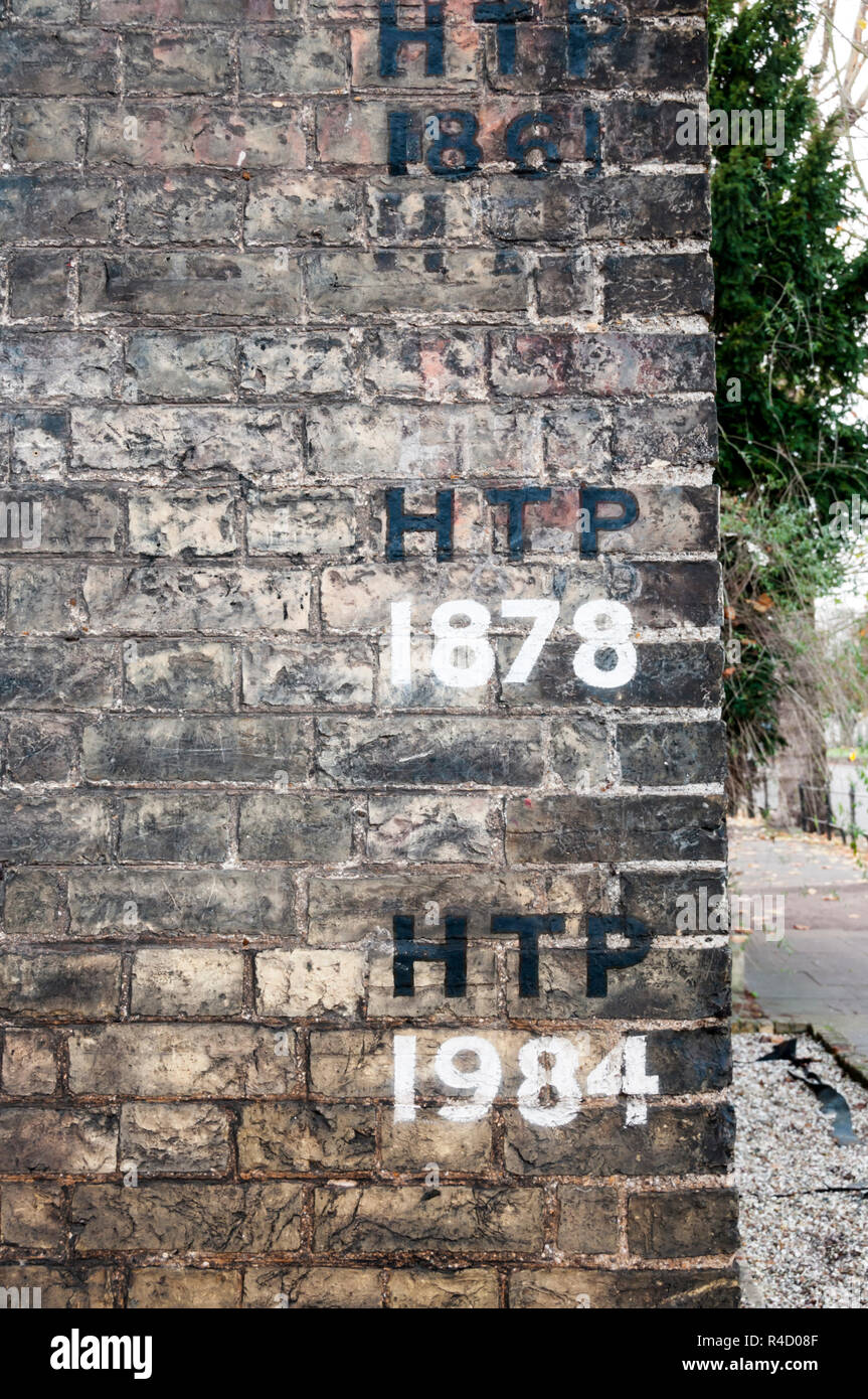 Contrassegni di confine per la Santa Trinità parrocchia su un muro di mattoni in Cambridge. Foto Stock