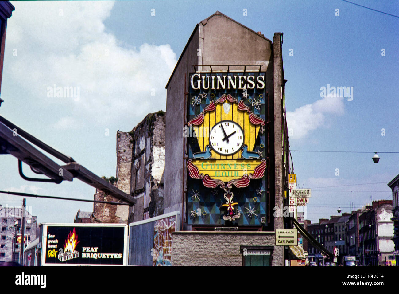 Pubblicità della Guinness e un orologio sul lato di Irwin fratelli orologeria e gioielleria che ha aperto nel 1897 a 22 Patrick Street, (R445), Limerick, County Limerick, Irlanda. La zona è stato rigenerato in quanto questa immagine originale presa entro i sessanta ma dopo aver cercato su Google maps il negozio sembra ora chiuso. Foto Stock