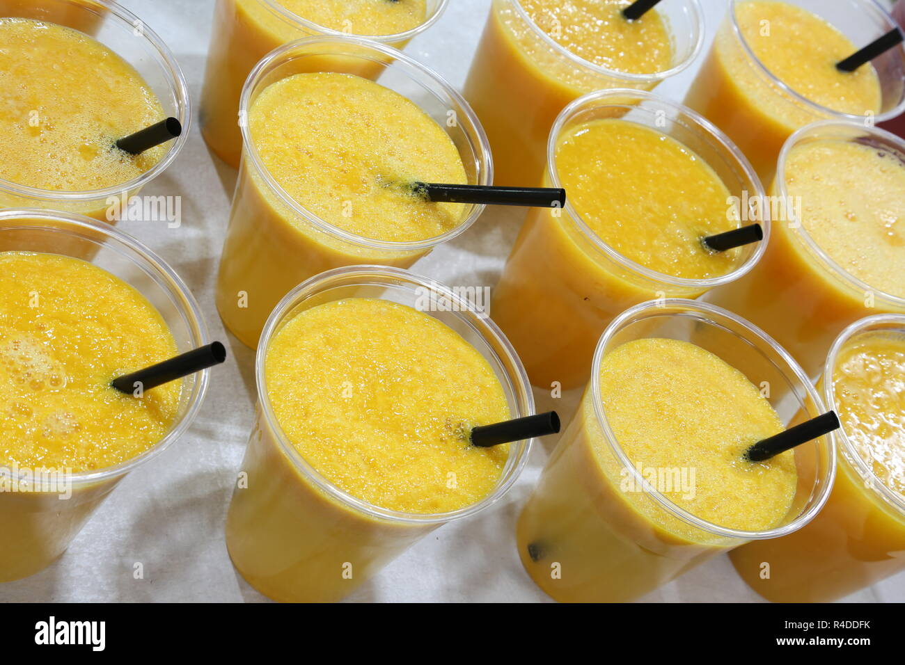 Molte tazze di plastica con sani succhi di arancia sul tavolo da buffet Foto Stock