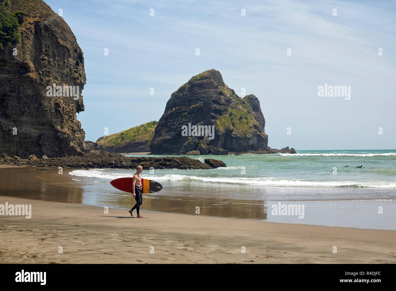 Uomo con una tavola da surf a Piha Beach, Nuova Zelanda Foto Stock