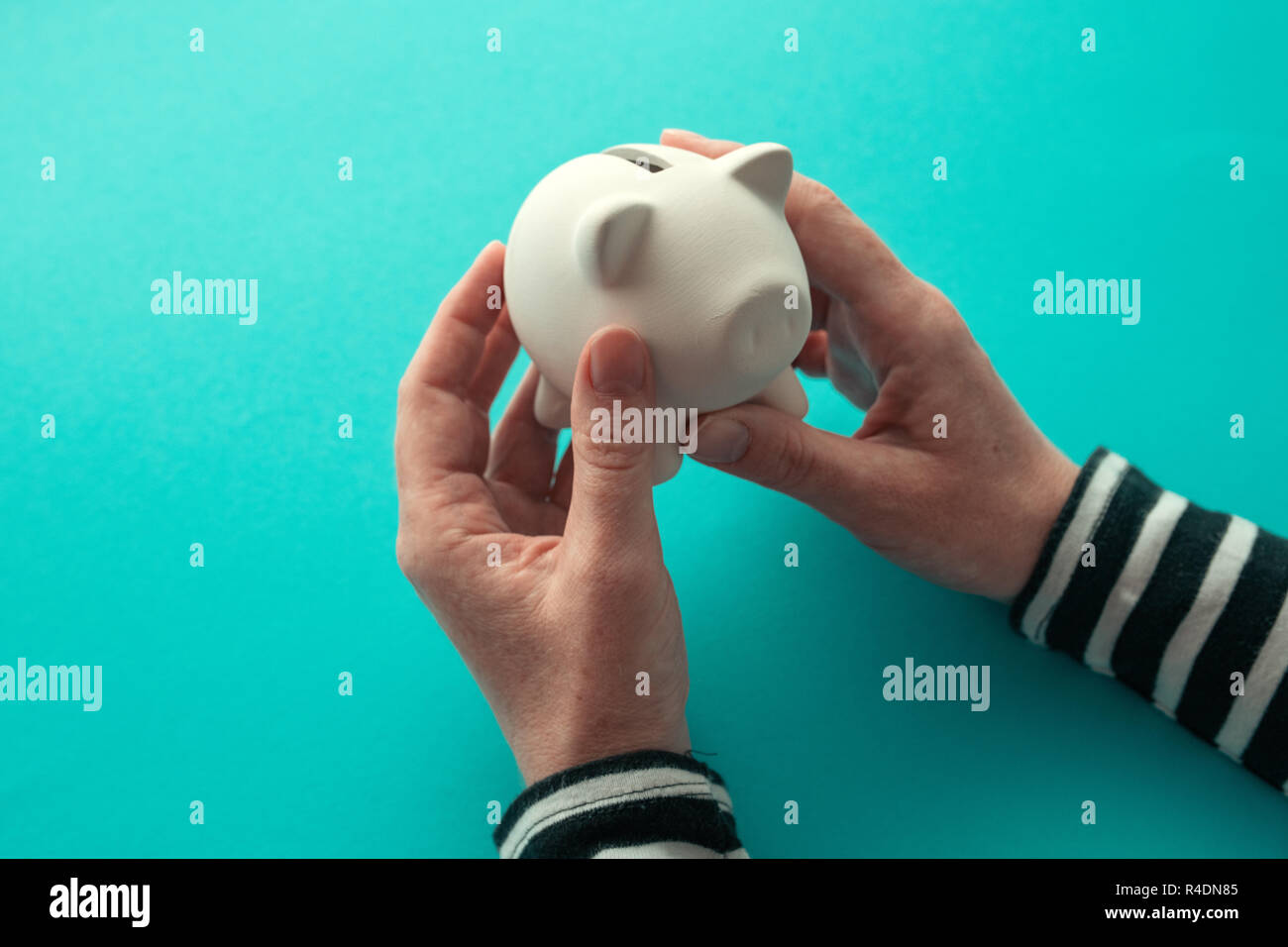 Mani femminili e piggy moneta della banca per il risparmio di denaro concept Foto Stock