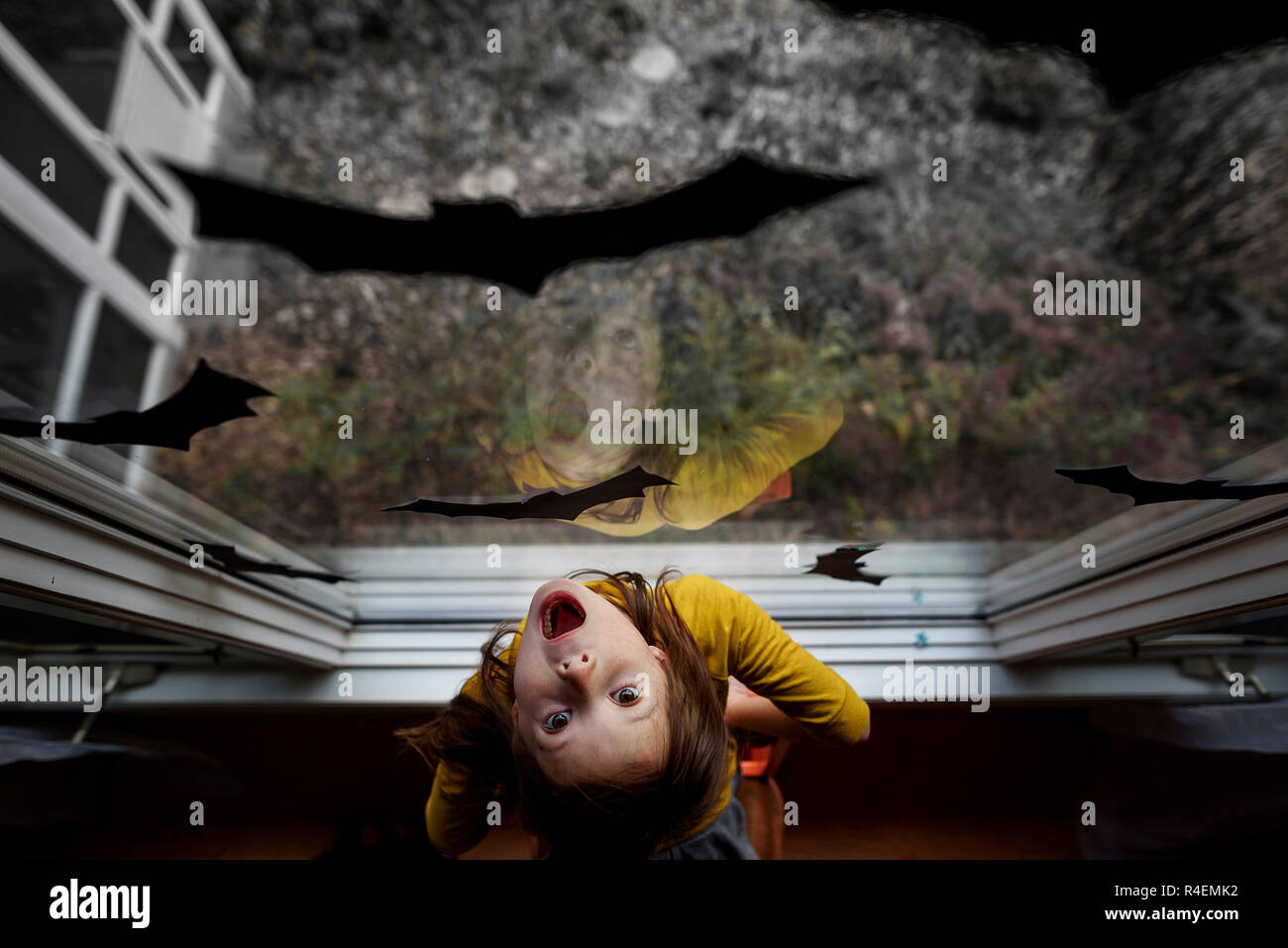 Vista aerea di una ragazza in piedi da una finestra decorata con bat decorazioni per Halloween, Stati Uniti Foto Stock