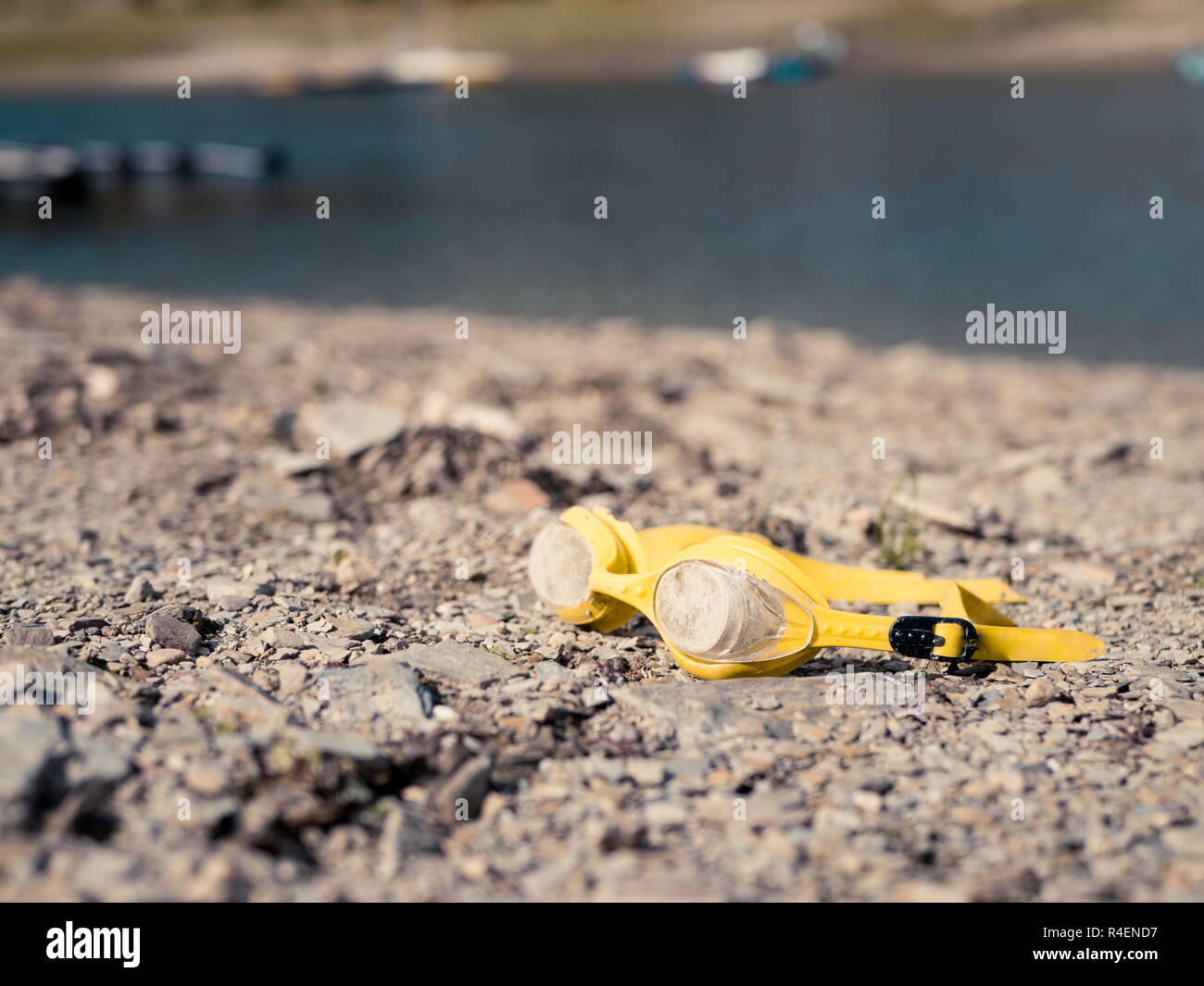 Vecchio e sporco giallo occhiali da nuoto giacente su una spiaggia Foto Stock