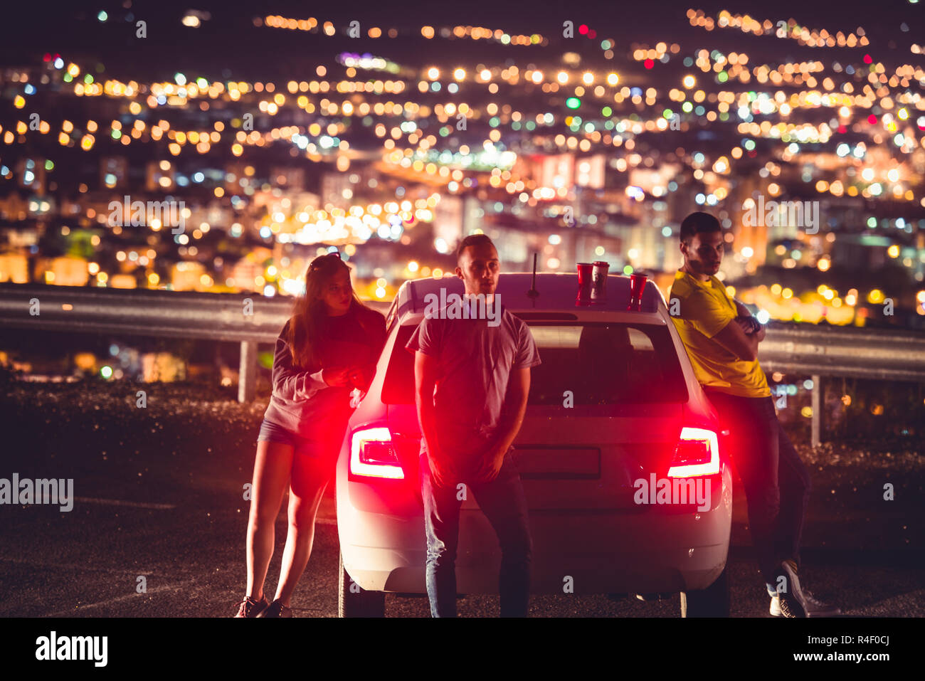 Gli amici di notte sono in piedi accanto a loro auto e godendo la vista e  le luci della città Foto stock - Alamy