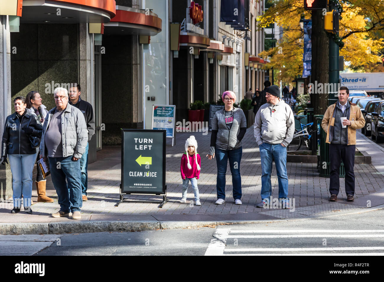 CHARLOTTE, NC, Stati Uniti d'America-11/21/18: 8 persone in attesa di cross street, tra cui un bambino piccolo con un inverno slittino. Foto Stock