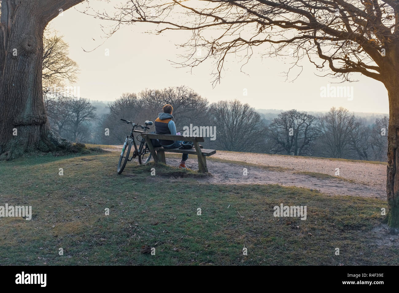 L'Inghilterra,Greater London,Richmond Park- ciclista avente un riposo su una panchina nel parco Foto Stock