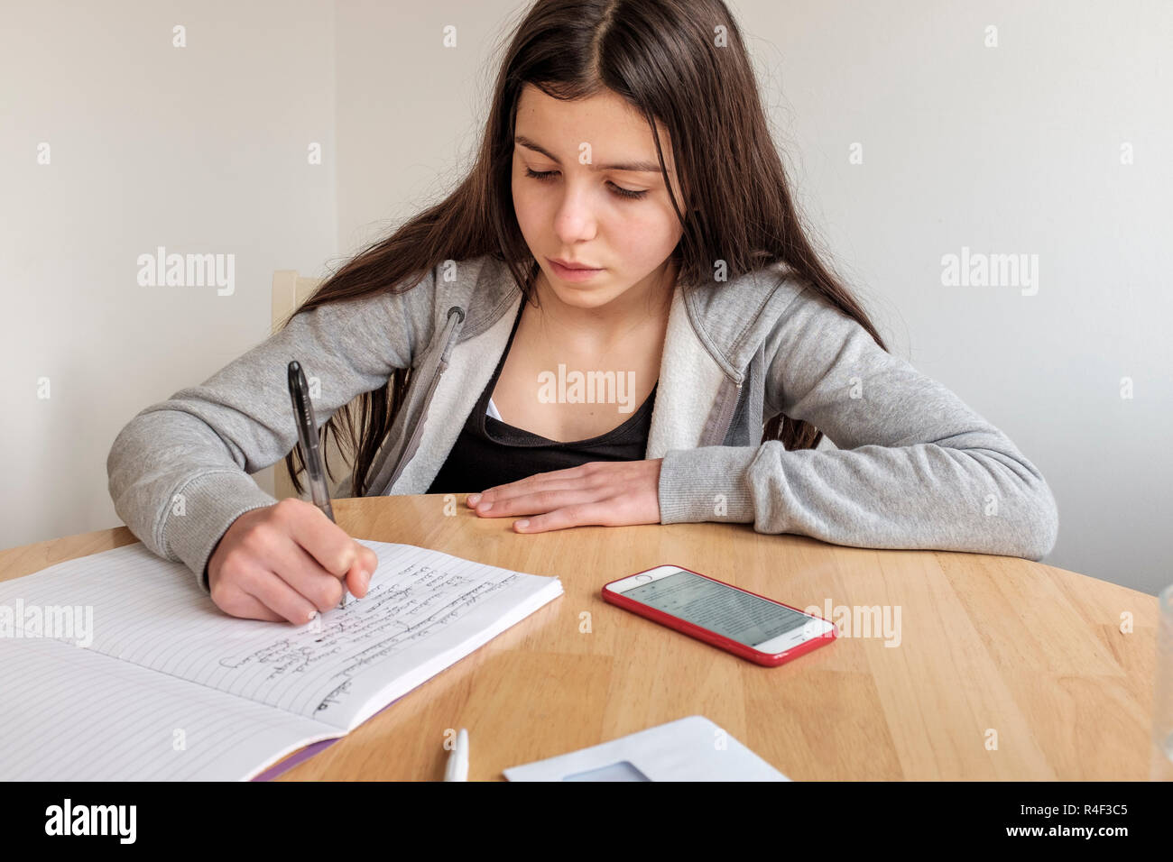 Inghilterra, Surrey-Schoolgirl, età 13 anni facendo i suoi compiti e la ricerca sul suo smartphone Foto Stock