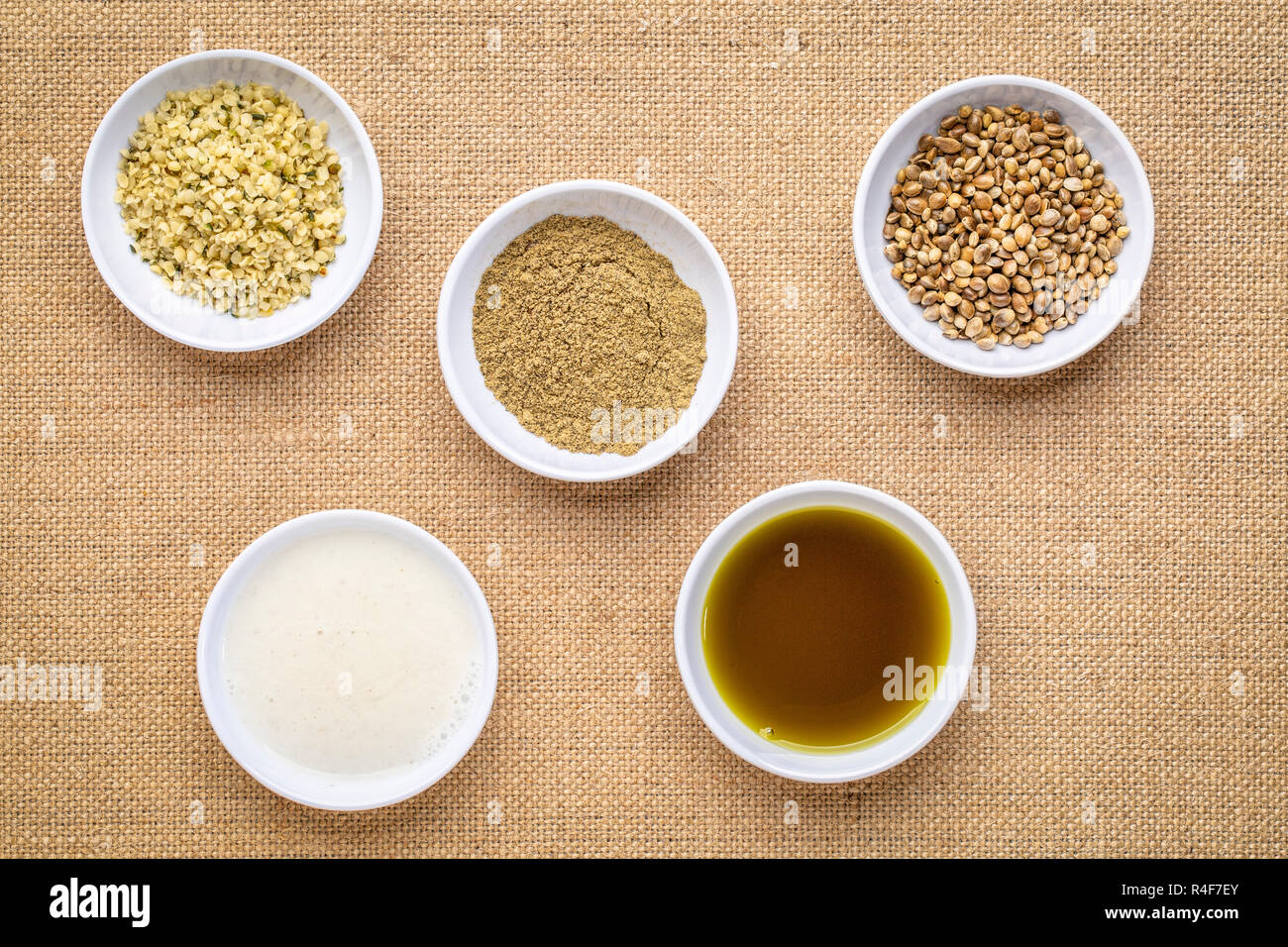 La raccolta di semi di canapa prodotto: cuori, proteine in polvere, latte e olio in piccole ciotole bianco contro la tela Canvas Foto Stock