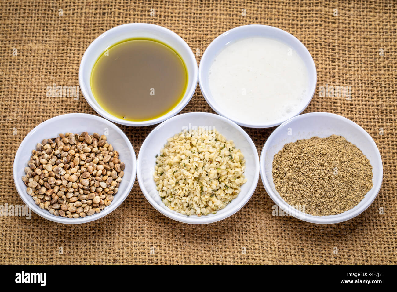 La raccolta di semi di canapa prodotto: cuori, proteine in polvere, latte e olio in piccole ciotole bianco contro Tela canvas Foto Stock