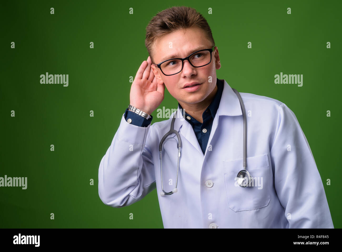Giovane uomo bello medico contro lo sfondo di colore verde Foto Stock