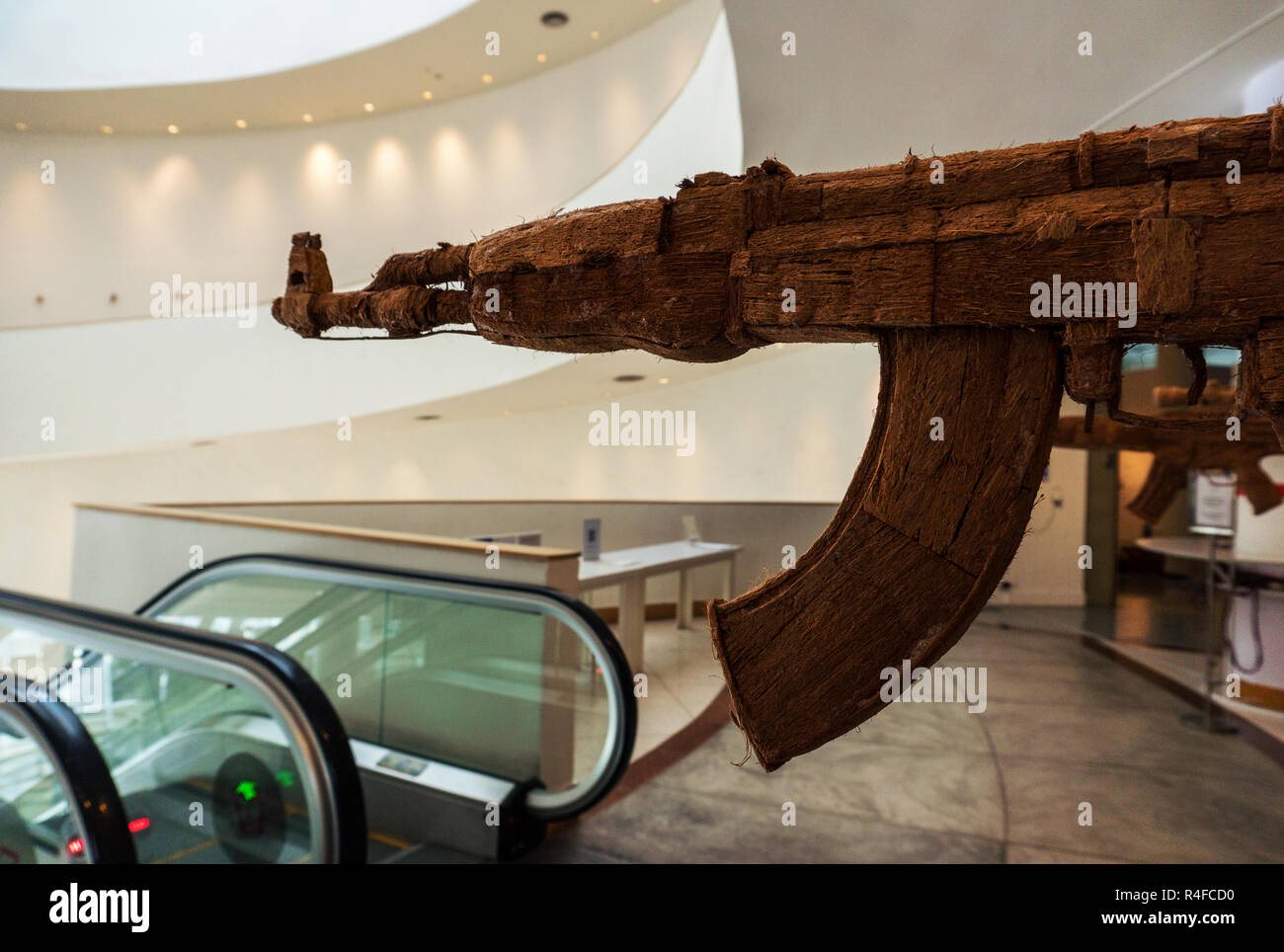 Thailandia, Bangkok - Febbraio 2018: Fake AK Kalashnikov fucile da assalto appeso davanti di escalator in Contemporary Arts Museum Foto Stock