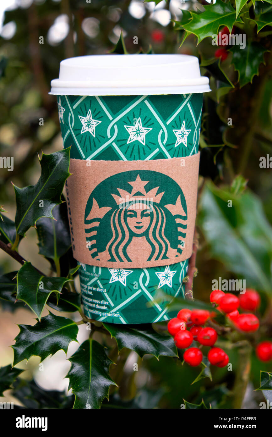 Starbucks di Natale carta festosa tazza da caffè e rosse bacche di agrifoglio in holly tree Gran Bretagna, Regno Unito Foto Stock