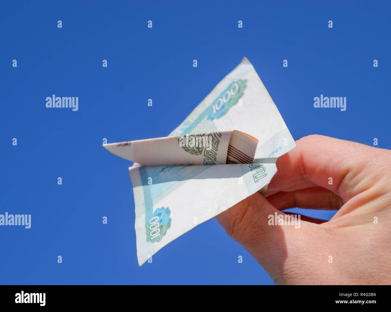 Tagli di denaro Russo, piegato in aeroplano contro il cielo blu in mano Foto Stock