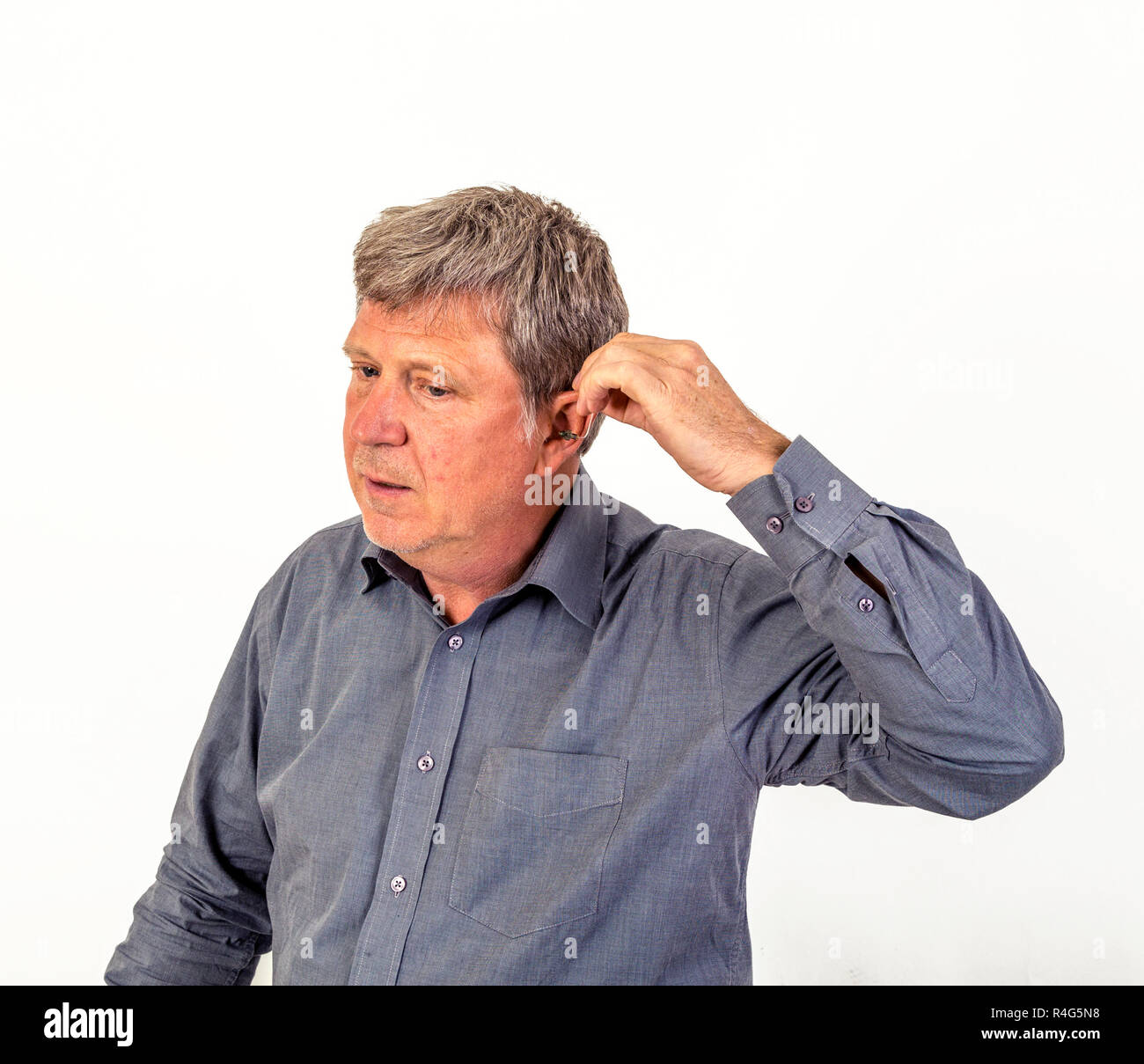 L'uomo mette hearing aid nell'orecchio Foto Stock