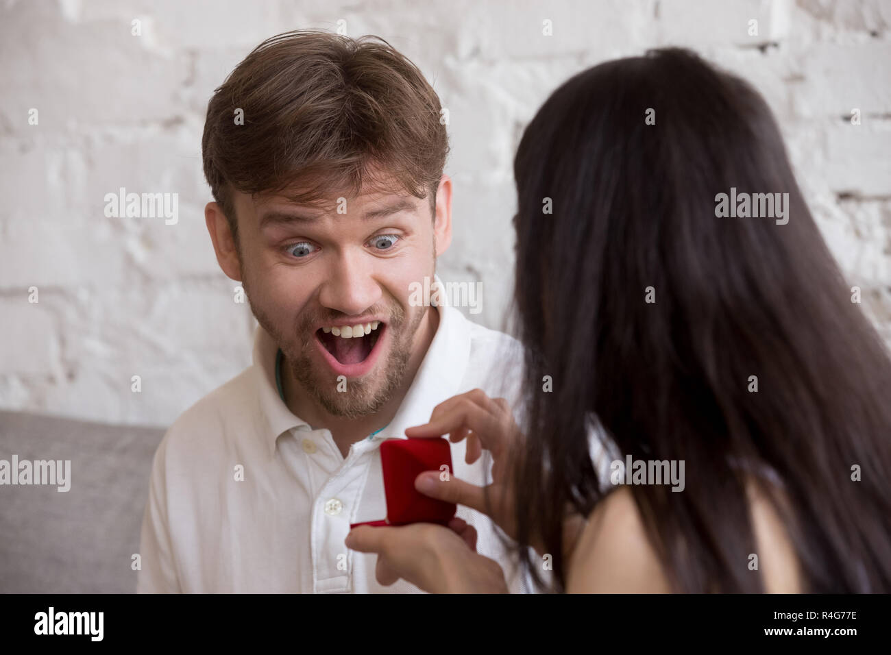 Donna facendo proposta di entusiasti sorpreso uomo felice Foto Stock