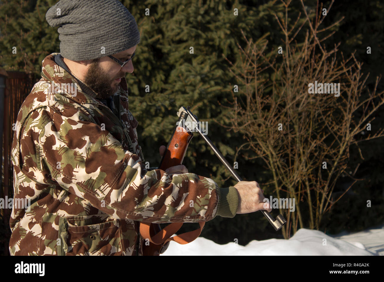 L uomo nella foresta invernale ricarica armi pneumatico. hunter vestito in camuffamento con pistola pneumatica,rifle Foto Stock