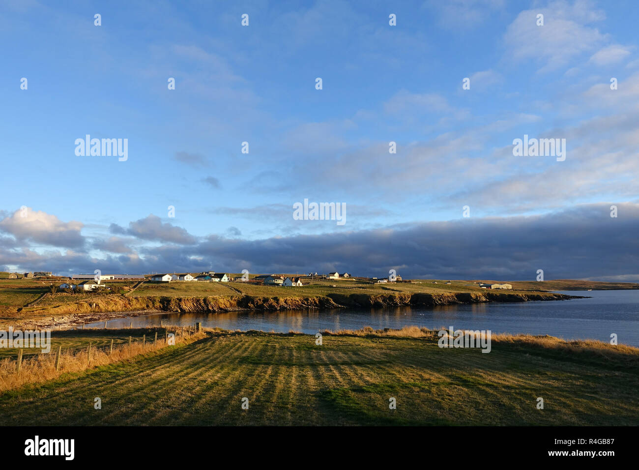 Bassa luce invernale in Sandwick Hoswick Shetland con case intorno le scogliere e la fascia costiera del villaggio Foto Stock