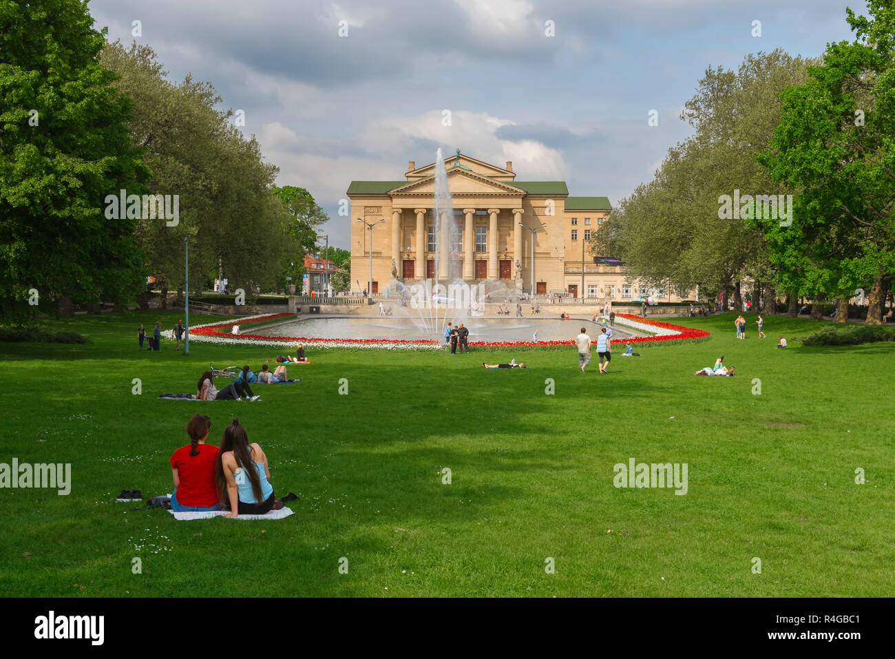 Parco estate città, vista in estate dei giovani rilassarsi nel Parco Mickiewicza guardando verso il teatro Poznan città (Teatr Wielki), Polonia Foto Stock