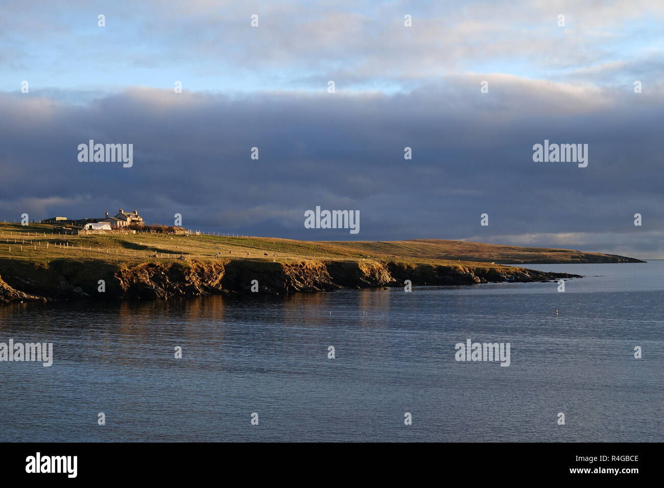 Bassa luce invernale in Sandwick Hoswick Shetland con case intorno le scogliere e la fascia costiera del villaggio Foto Stock