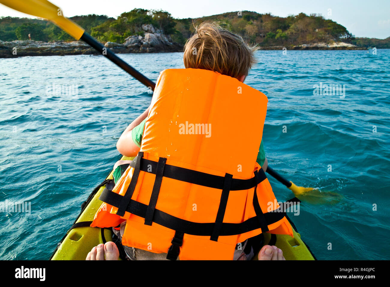 Ragazzo paddling in una canoa all'oceano con sicurezza ad ovest Foto Stock