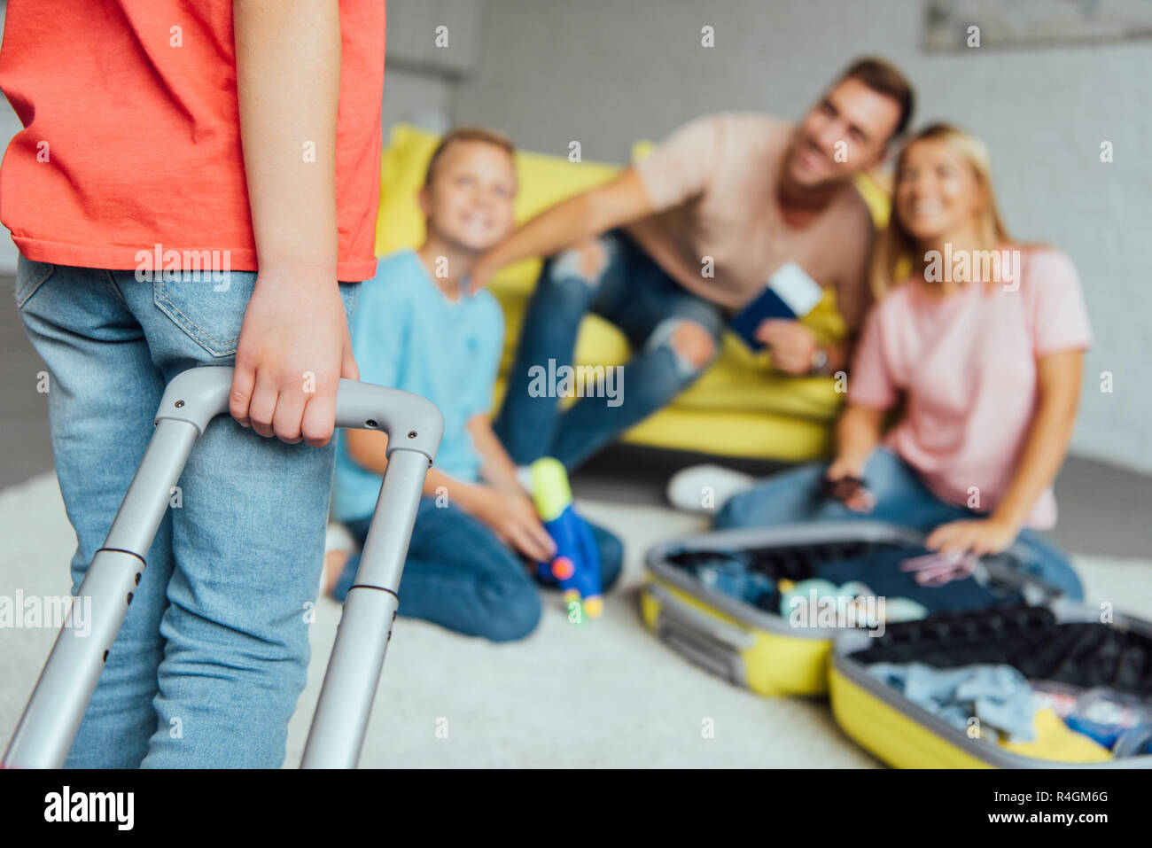 Kid holding valigia mentre la famiglia imballaggio per le vacanze estive sul background, concetto di viaggio Foto Stock