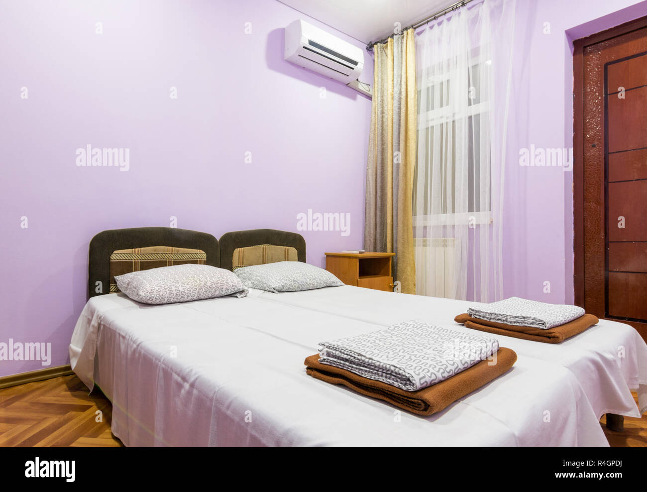 L'interno di una piccola camera con un letto matrimoniale, una finestra e splitsistema Foto Stock