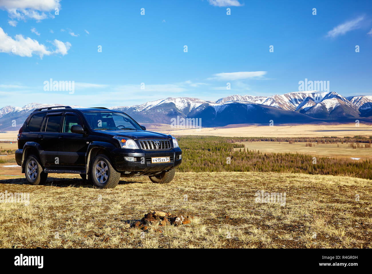 KURAI, Russia - 27 Maggio 2015: Nero Land Cruiser Prado in Altai montagne in area Kurai con Nord Chuisky Ridge su sfondo. Foto Stock