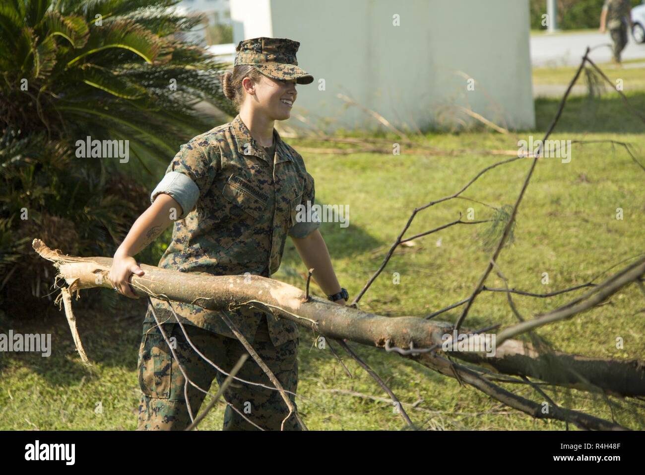 Stati Uniti Marine Corps Cpl. Elana Merrimarahajara, un geometra con sede e supporto battaglione, Marine Corps Impianti Pacific-Marine Corps Base Camp Butler, Giappone, porta un albero caduto il ramo al 1 ottobre 2018, nel corso di una pulizia di base su Camp Foster, Okinawa, in Giappone. La pulitura è stata condotta dopo il tifone Trami colpito l'isola. Marines e marinai hanno lavorato insieme per rimuovere i rami degli alberi e i detriti dal intorno alla base. Foto Stock