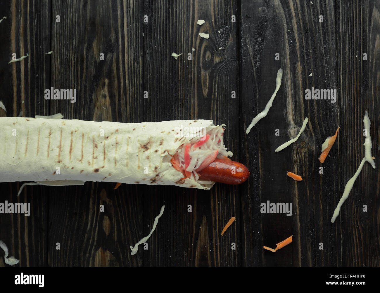 Salsicce e insalata avvolto in lavash su sfondo di legno.foto Foto Stock