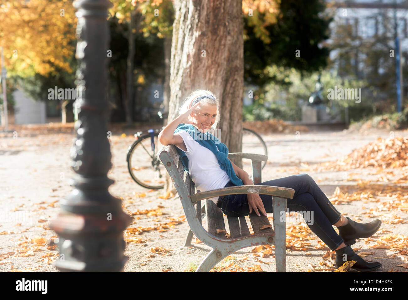 Donna sorridente seduto su una panchina nel parco, Germania Foto Stock