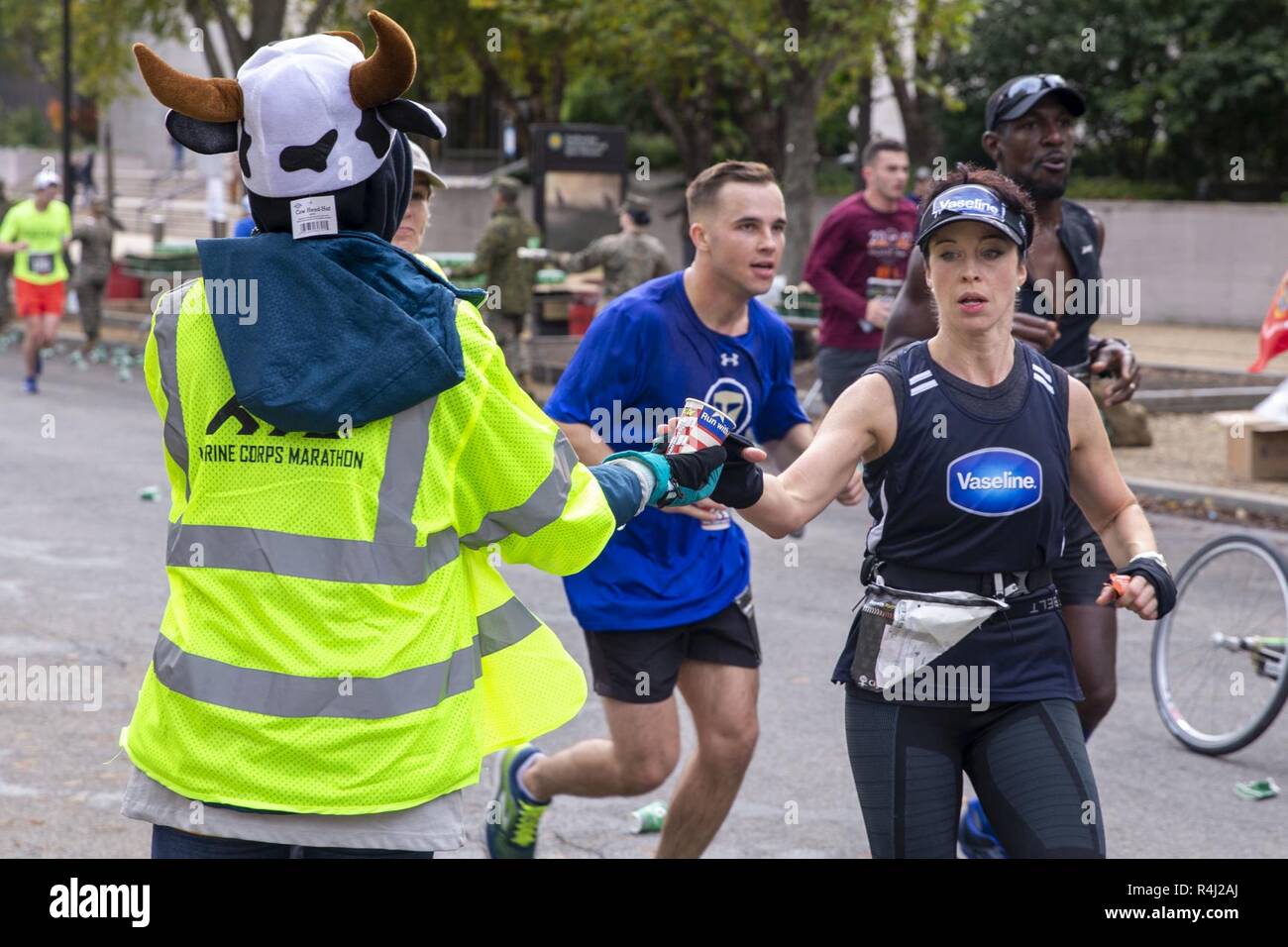 Un volontario dà una tazza di acqua per un runner durante l'annuale quarantaduesima Marine Corps Marathon, Washington D.C., 28 ottobre 2017. Noto anche come "popolo della maratona,' il 26,2 miglia race ha attirato circa 30.000 partecipanti per promuovere il benessere fisico, generare la buona volontà nella comunità e mostrare la capacità organizzativa del Marine Corps. Foto Stock