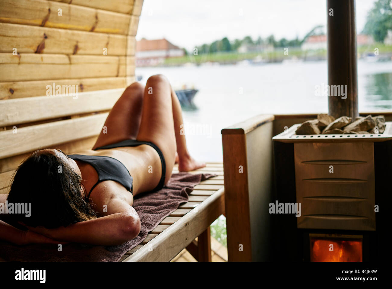 Metà donna adulta giacente in una sauna a Copenhagen, Danimarca Foto Stock
