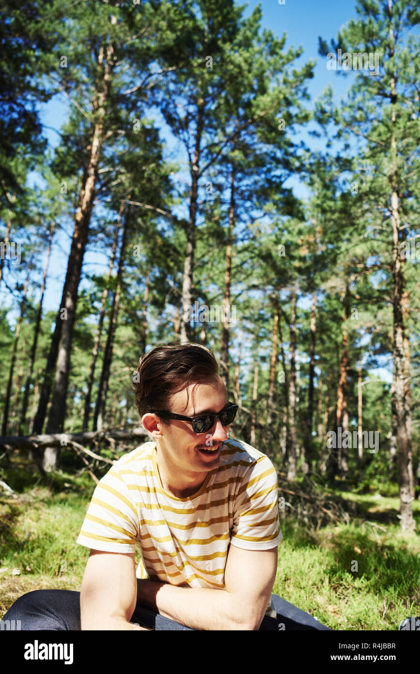 Giovane uomo seduto in una foresta in Djurgarden, Svezia Foto Stock