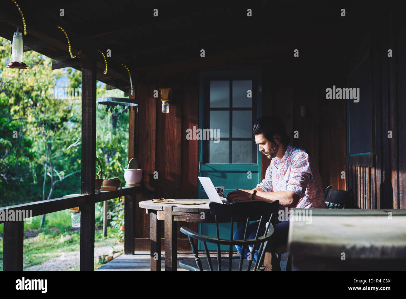 Metà uomo adulto utilizzando laptop in veranda Foto Stock