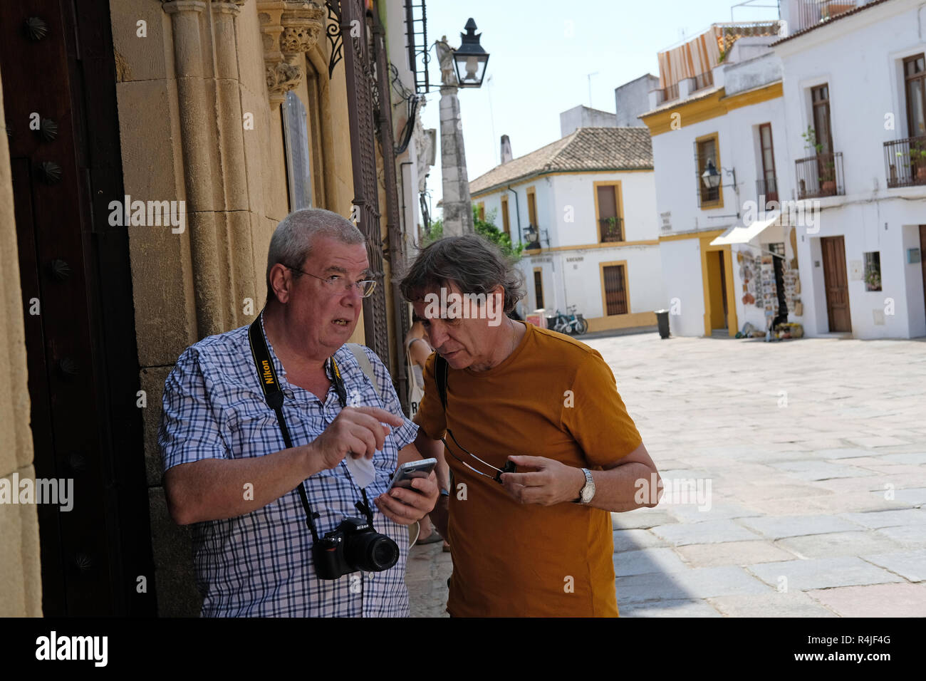 Due turisti che utilizzano i loro telefoni cellulari per le direzioni a Cordoba, Spagna. Foto Stock