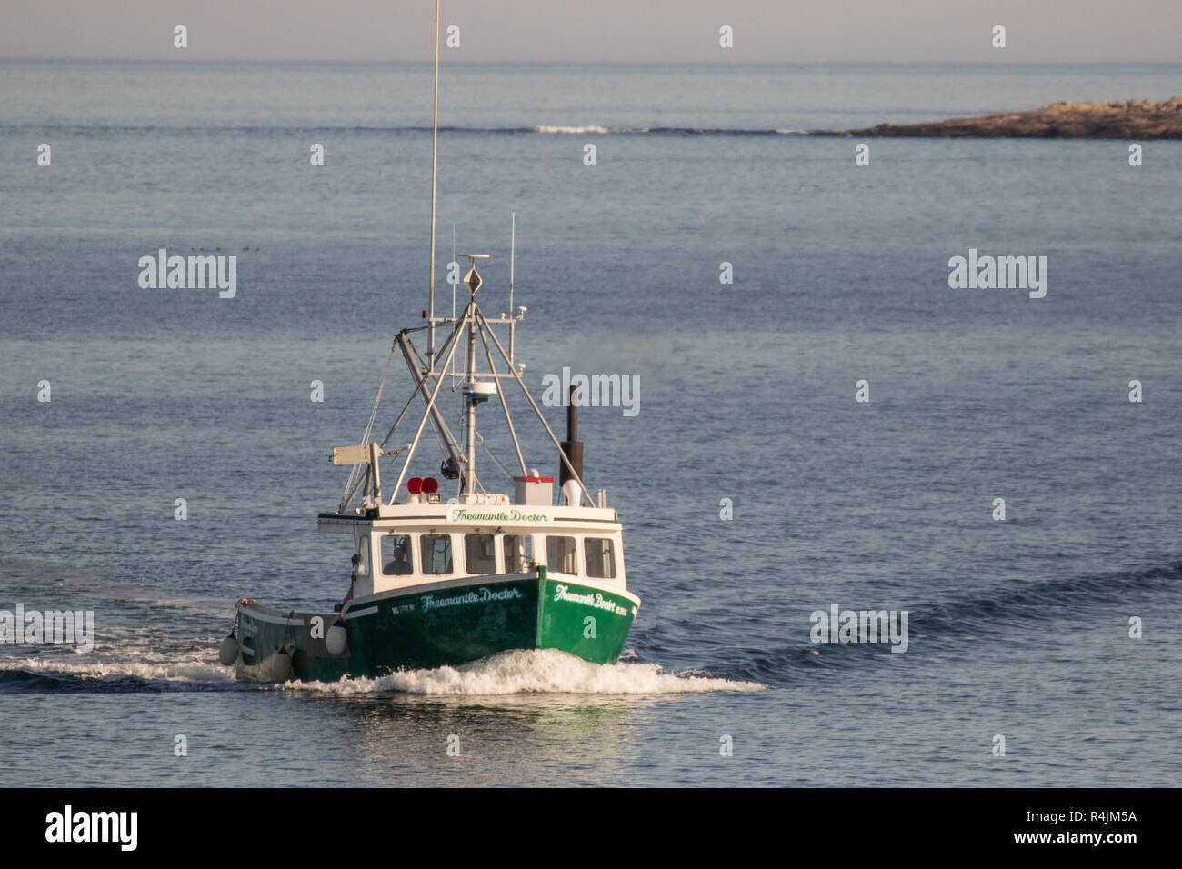 Barca da pesca in arrivo al porto vicino alla punta orientale faro in Gloucester, MA Foto Stock