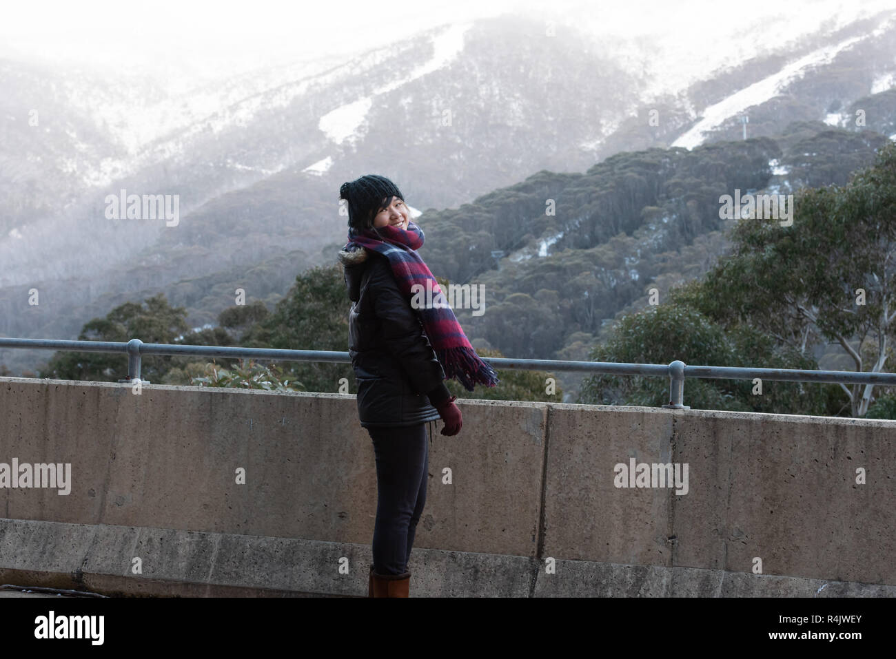 Giovane donna in posa di fronte della coperta di neve Mount Kosciuszko a Thredbo Foto Stock