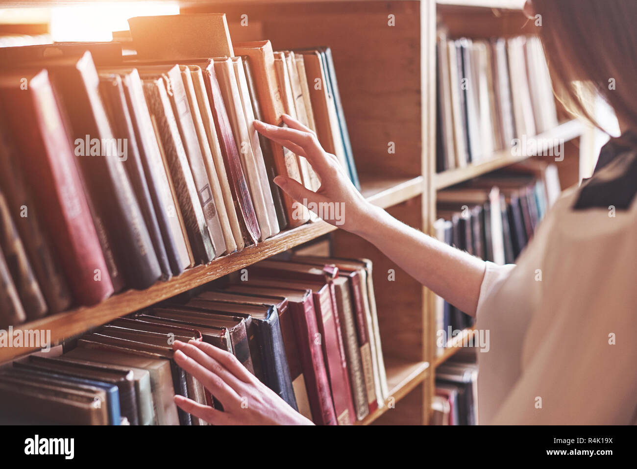 Giovane studente attraente bibliotecario leggendo un libro tra gli scaffali della libreria Foto Stock