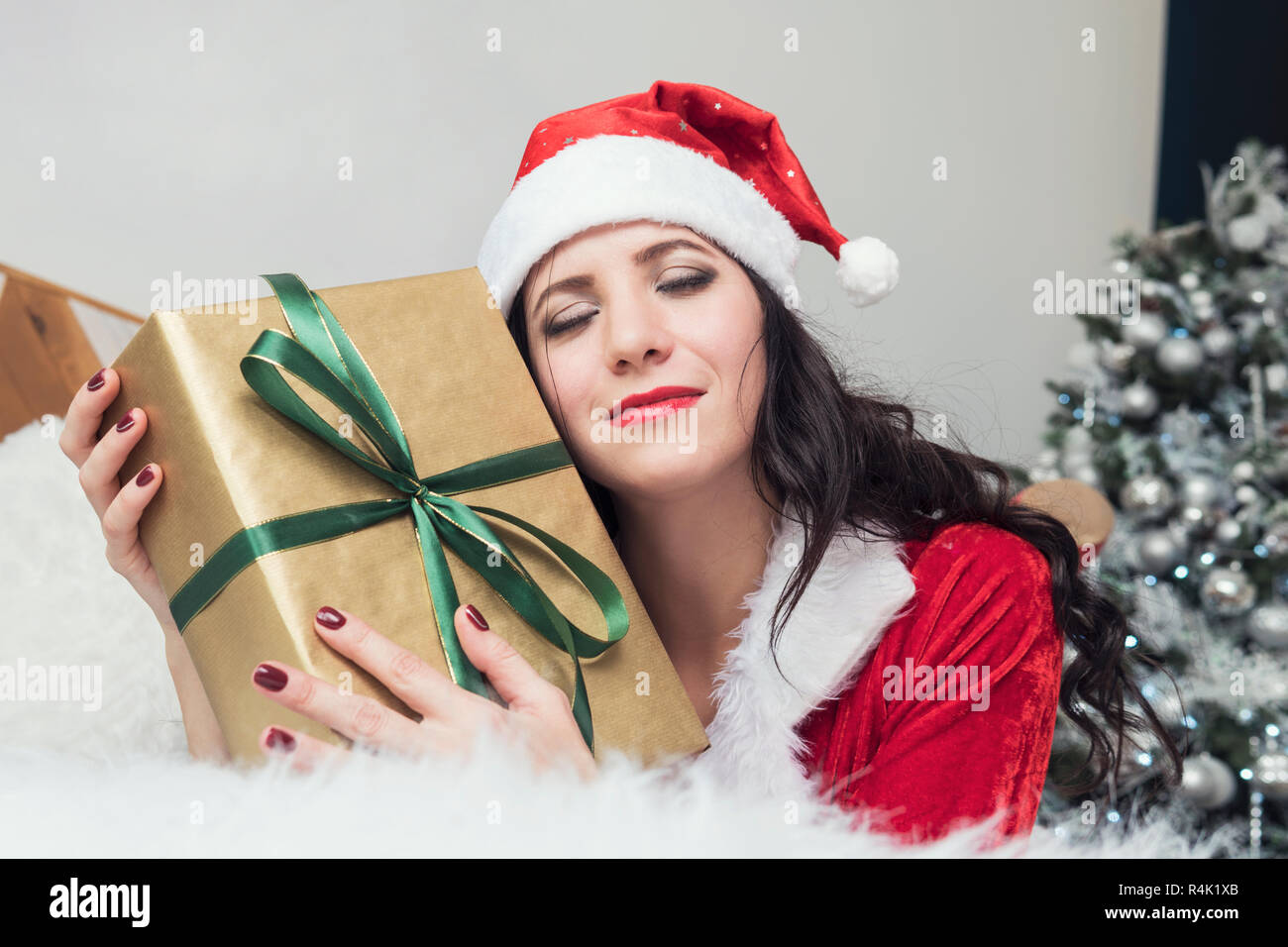 Sorridente ragazza adolescente in santa helper hat con molte confezioni regalo su sfondo bianco. Positivo emotivo Santa ragazza. Concetto di vendita e shopping di Natale. Xmas. Ragazza abbracciando doni. Foto Stock