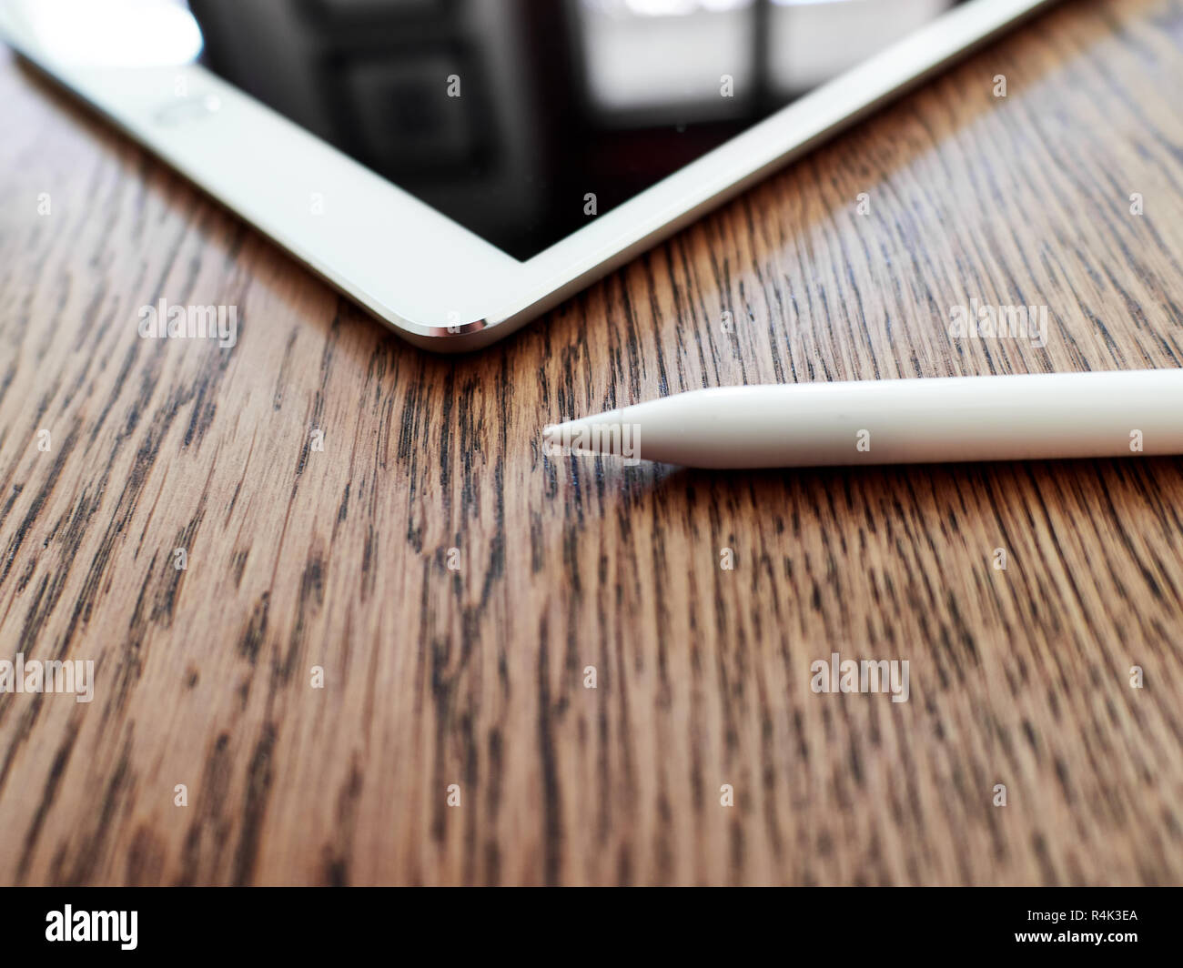 Matita di Apple e il suo cappuccio su un iPad di colore bianco su una superficie in legno Foto Stock