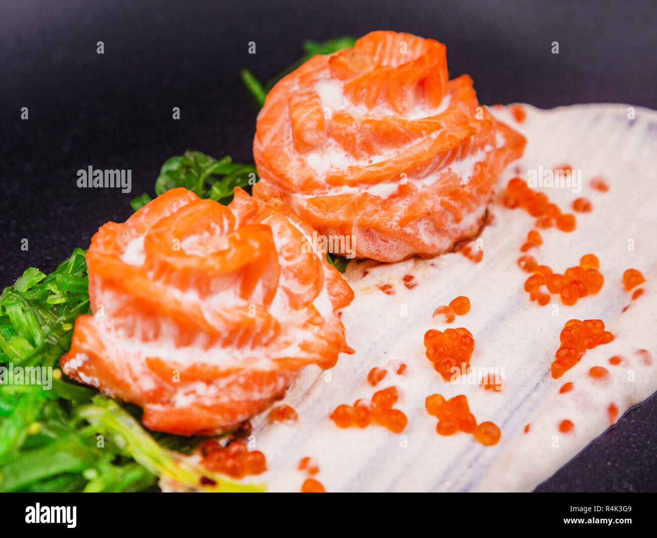 Piatto con salmone hiyashi alghe e caviale rosso su sfondo scuro, close up Foto Stock