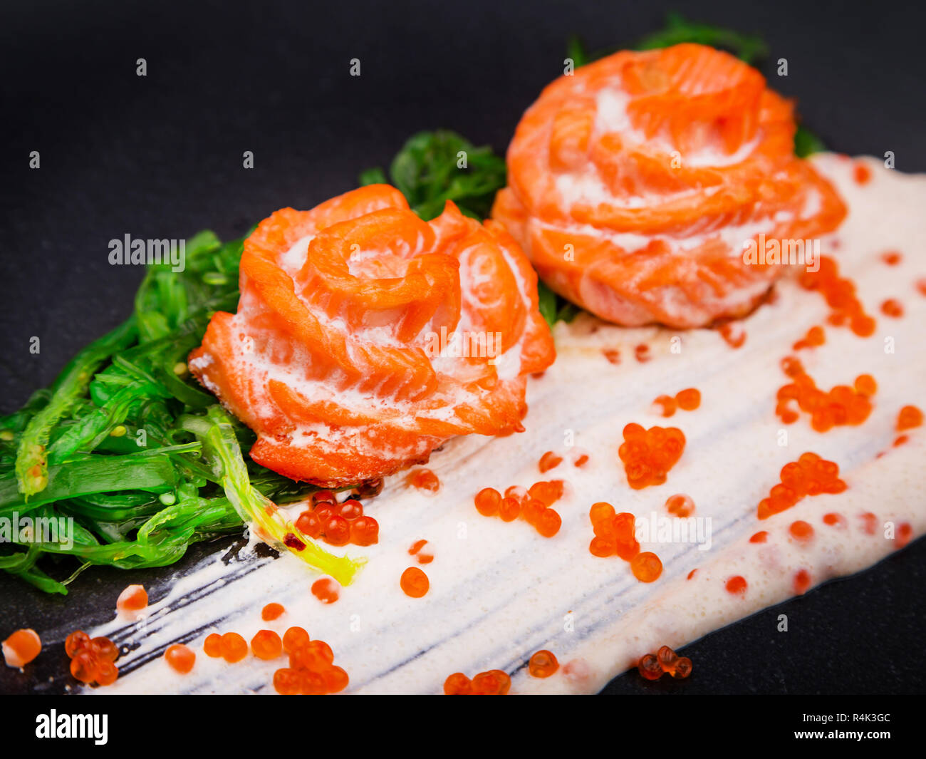 Close up piatto di salmone in salsa di panna e guarnita con hiyashi alghe e caviale rosso Foto Stock