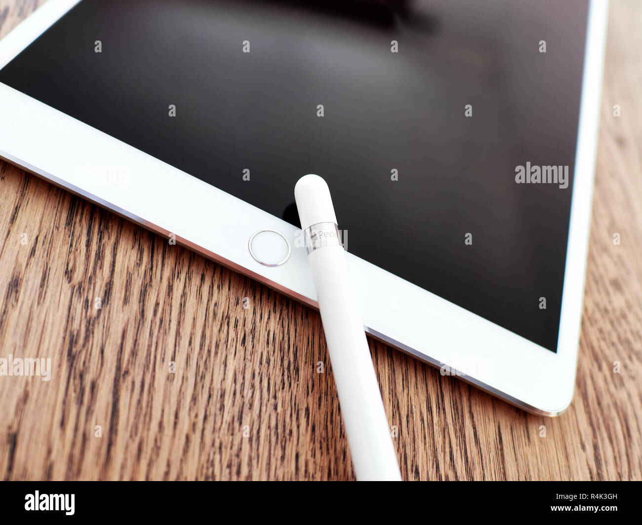 Matita di Apple e il suo cappuccio su un iPad di colore bianco su una superficie in legno Foto Stock